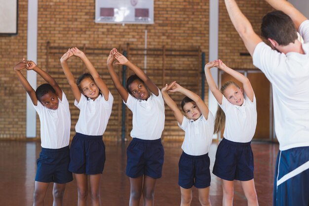 Lehrerunterrichtsübung für Schulkinder im Basketballplatz