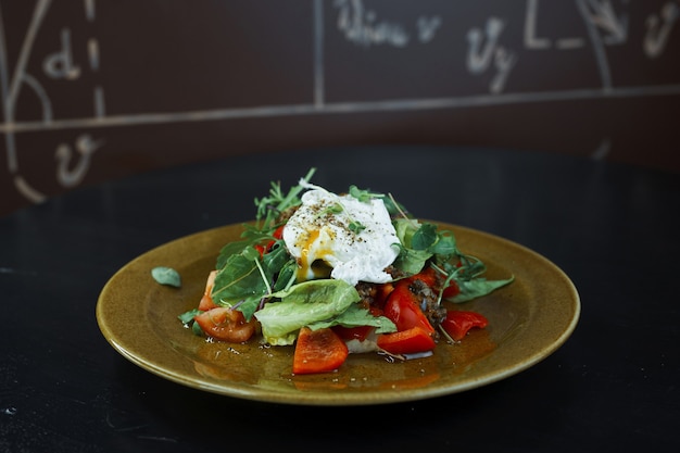 Leichter kalorienfreier Diät-Salat mit frischen Tomatenscheiben mit Petersilie, Rucola, pochiertem Ei und Olivenöl. Köstlicher gesunder Snack. Vegetarisches Essen