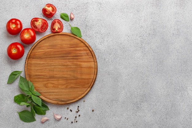 Leichter kulinarischer Hintergrund mit runden Holzbretttomaten und Basilikum