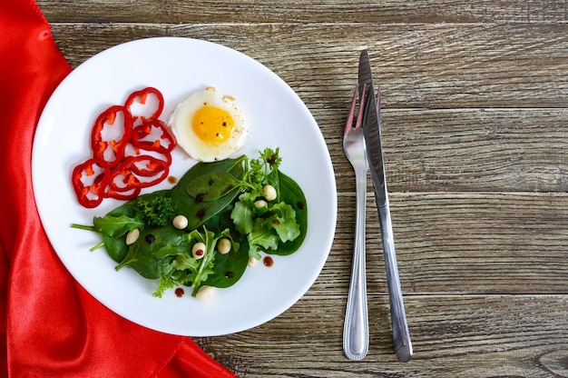 Leichtes Frühstück - Wachtelei, grüner Salat, Paprika auf einem Holztisch. Ansicht von oben. Gesundes Essen. Richtige Ernährung.