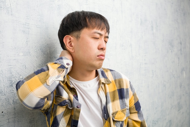 Leiden Nackenschmerzen der jungen chinesischen Manngesichtsnahaufnahme