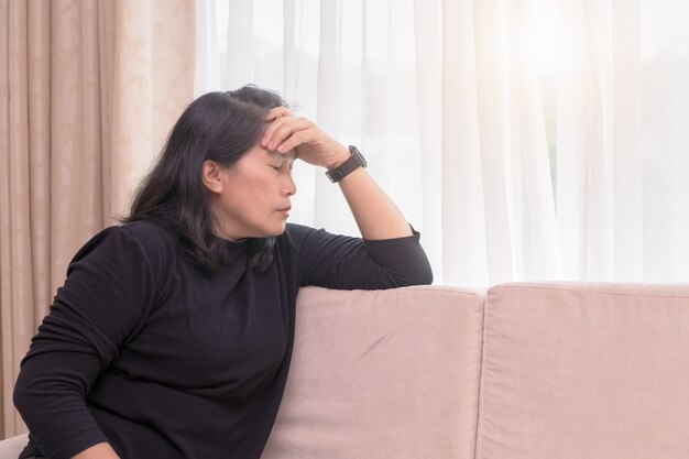 Leidende Kopfschmerzen der Frau, die auf einem Sofa sitzen