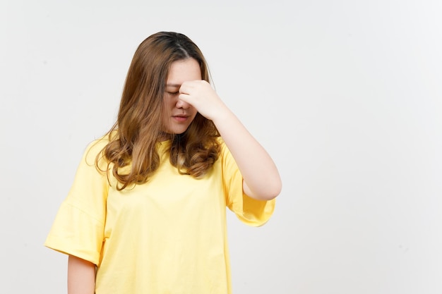 Leidende Kopfschmerzen der schönen asiatischen Frau, die gelbes T-Shirt lokalisiert auf weißem Hintergrund trägt