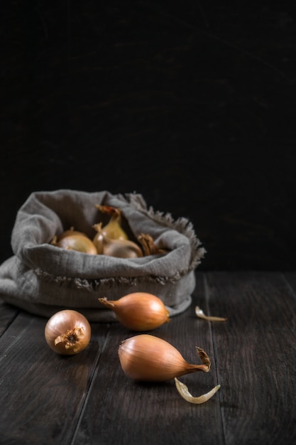 Leinensack mit Zwiebel auf dem Holztisch. Selektiver Fokus