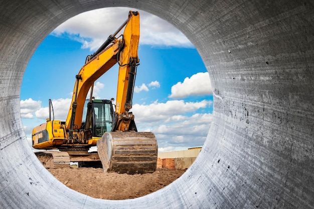 Leistungsstarker Bagger auf der Baustelle Blick auf den Bagger durch das Rohr Nahaufnahme von Erdbewegungsmaschinen Baumaschinen für Erdarbeiten Bodenentwicklung