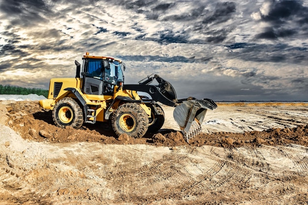 Leistungsstarker Bulldozer oder Lader bewegt die Erde auf der Baustelle gegen den Himmel Eine Erdbewegungsmaschine nivelliert die Baustelle Schwere Baumaschinen für Erdarbeiten