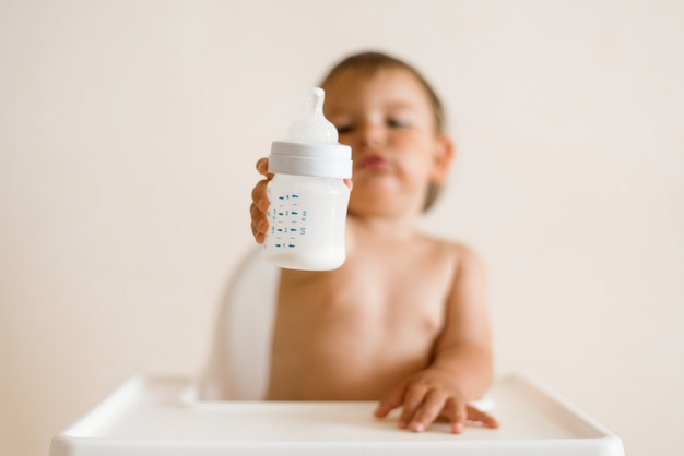 Foto leite bebendo do bebê adorável de uma garrafa da garrafa.