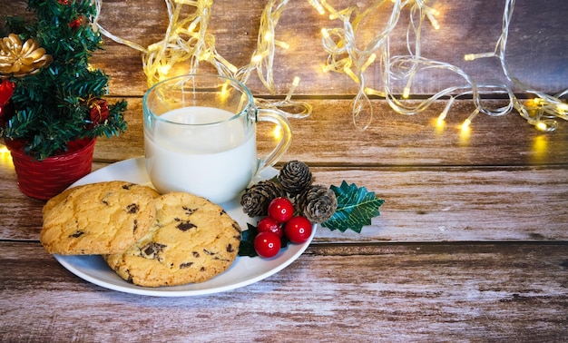 Leite com biscoitos de natal para o Papai Noel em foco seletivo de mesa de madeira