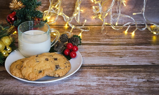 Leite com biscoitos de natal para o papai noel em uma mesa de madeira, foco seletivo.