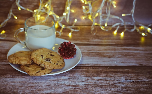 Leite com biscoitos de natal para o papai noel em uma mesa de madeira, foco seletivo.