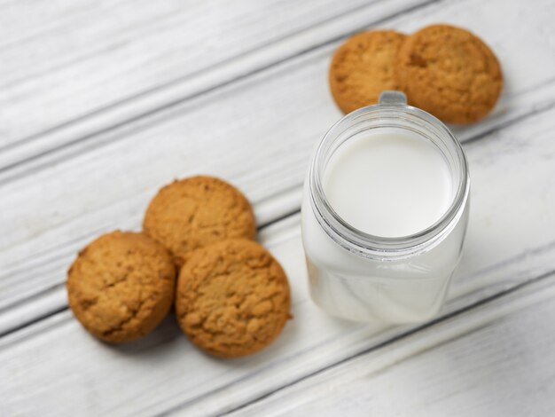 Leite com biscoitos no fundo branco de madeira