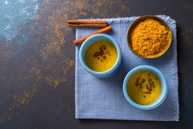 Leite de açafrão dourado com leite feito com açafrão e outras especiarias sobre fundo de madeira.