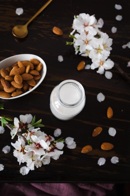 Foto leite de amêndoa com amêndooas e flores de amêndoas na mesa a alternativa vegana ao leite tradicional