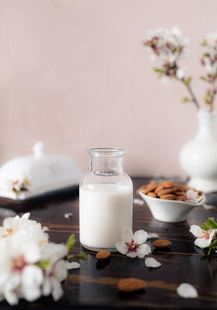 Foto leite de amêndoa com amêndooas e flores de amêndoas na mesa a alternativa vegana ao leite tradicional