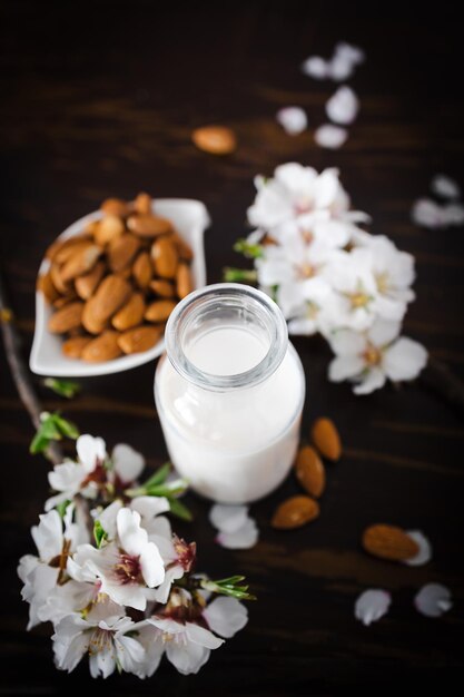 Leite de amêndoa com amêndooas e flores de amêndoas na mesa a alternativa vegana ao leite tradicional