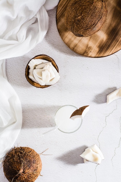 Leite de coco em um copo com canudo e pedaços de frutas tropicais na mesa Topo e vertical