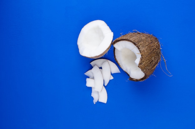 Leite de coco natural, lascas de coco, lascas de coco, sobre um fundo azul. O conceito de comida saudável.