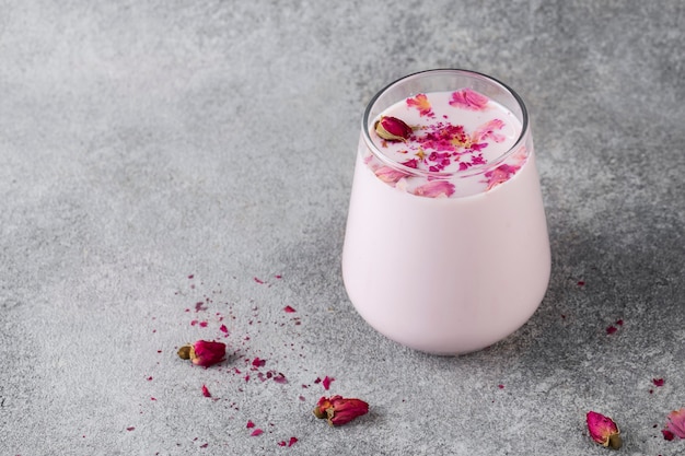 leite de lua rosa em copo, bebida relaxante à meia-noite, rosas, mesa cinza