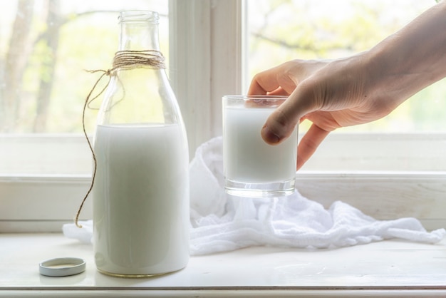 Leite de vaca cru fresco em um peitoril da janela, pequeno-almoço saudável na aldeia, despeje o leite nos vidros