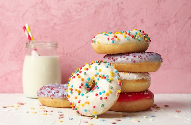 Leite e donuts saborosos contra um fundo rosa