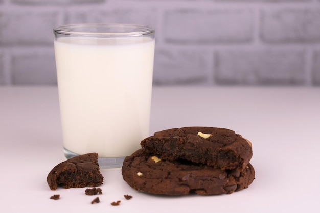 Leite em um copo e biscoitos caseiros de chocolate em um fundo branco