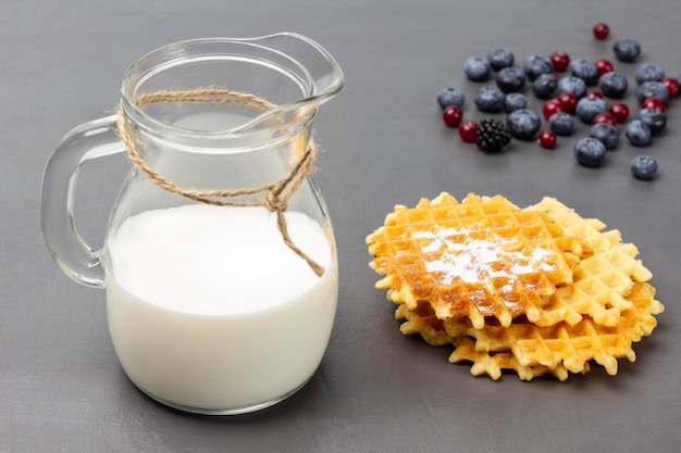 Leite na jarra de vidro Waffles e frutas na mesa