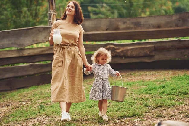 Leite natural fresco Jovem mãe com sua filha está na fazenda no verão