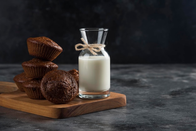 Leite numa tábua de madeira com biscoitos doces de chocolate de cacau