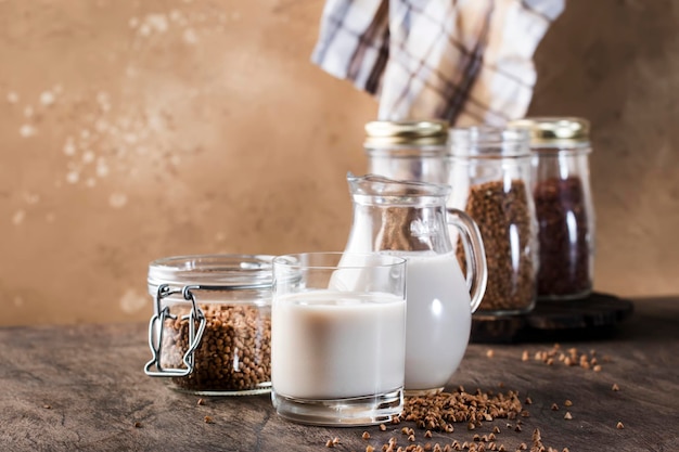 Leite vegano à base de plantas de trigo sarraceno em garrafas closeup fundo marrom Leite alternativo sem laticínios Conceito de comida e bebida vegetariana saudável Espaço de cópia