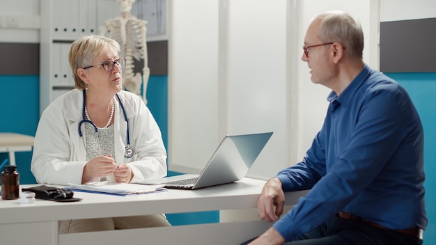 Leitender arzt, der bei einem termin in der arztpraxis an der konsultation eines kranken patienten teilnimmt und die diagnose auf genesung untersucht. checkup-besuch, um verschreibungspflichtige behandlung, gesundheitssystem zu finden.