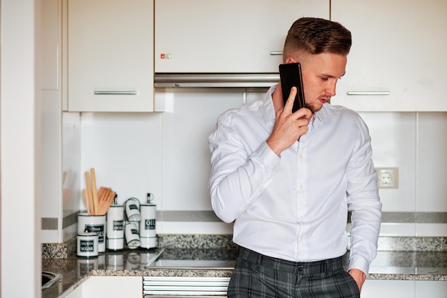 Leitender Geschäftsmann, der am Telefon spricht, während er in einer Küche steht