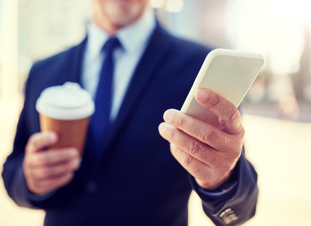 leitender Geschäftsmann mit Smartphone und Kaffee