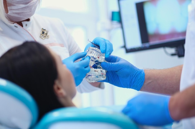 Leitender männlicher Zahnarzt in der Zahnarztpraxis, der mit Patientin spricht und sich auf die Behandlung vorbereitet