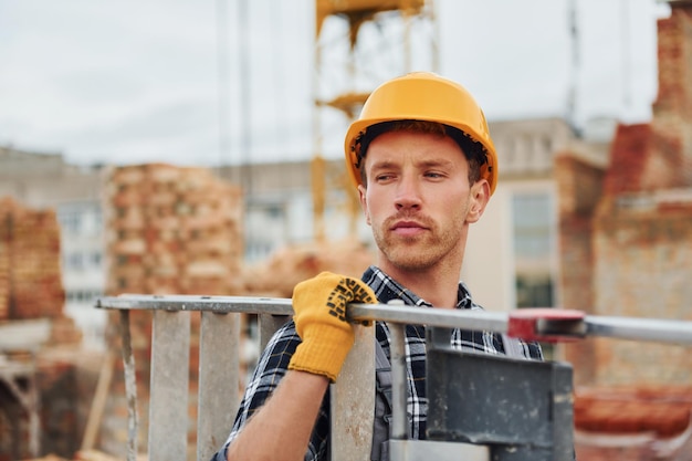 Leiter in Händen Bauarbeiter in Uniform und Sicherheitsausrüstung haben Arbeit am Bau