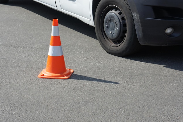 Leitkegel mit weißen und orangefarbenen Streifen auf grauem Asphalt mit Kopierraum für Autoräder Helles Wetter