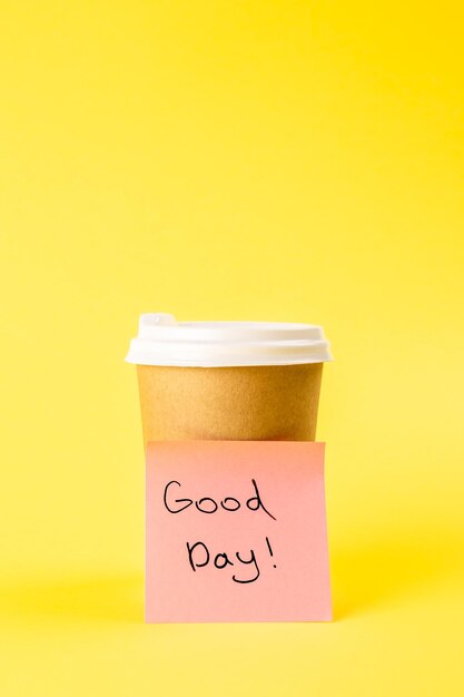 Lembrete de xícara e papel com bom dia de inscrição em um fundo amarelo