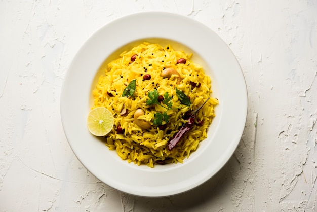 Lemon Rice ou fodnicha bhat é arroz com cúrcuma do sul da Índia ou receita maharashtrian usando sobras de arroz guarnecido com folhas de curry de nozes e suco de limão, foco seletivo