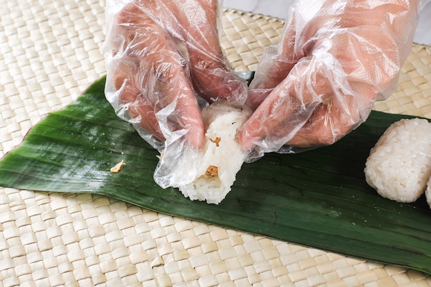 Lemper Ayam, refrigerio indonesio hecho de arroz glutinoso relleno con pollo desmenuzado sazonado envuelto en hoja de plátano. Lemper en forma de mano femenina