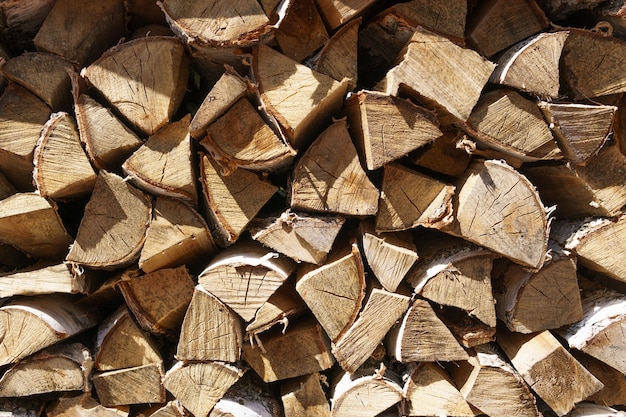 Leña apilada una encima de la otra. Fondo de troncos de madera.