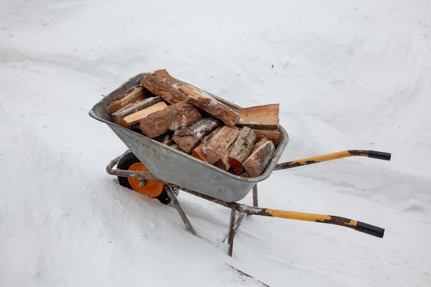 Leña para la estufa en un carro en un camino nevado en invierno Concepto de calidez y confort en el hogar Calefacción alternativa