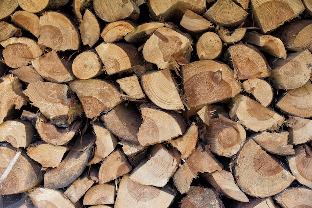 Leña marrón seca troncos de madera picada o pilas apiladas para el invierno sobre fondo de madera