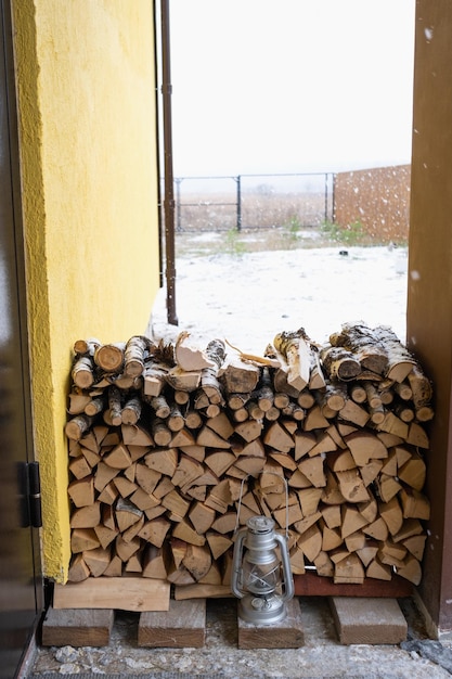 La leña en el porche nevado de la casa se cosecha para el invierno Calefacción de viviendas con estufa chimenea ahorro de electricidad y gas en una crisis respeto al medio ambiente