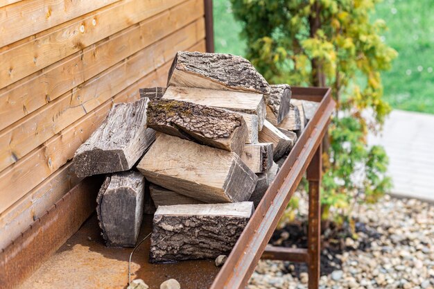 La leña de primer plano sobre un fondo de madera está perfectamente apilada en la zona de la barbacoa