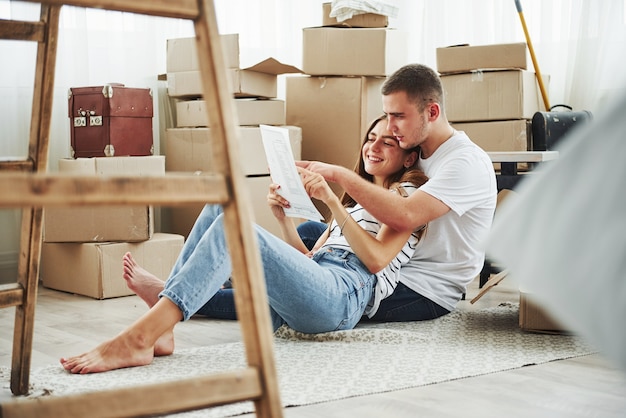 Lendo o documento. Casal jovem alegre em seu novo apartamento. Concepção de movimento.