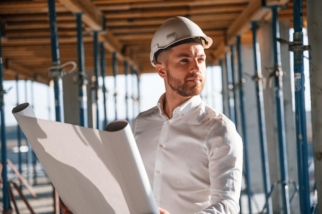 Foto lendo o plano o homem está trabalhando no canteiro de obras durante o dia