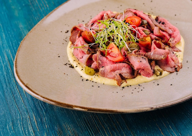 Lengua de ternera frita curada y troceada con puré de patata