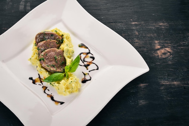 Lengua de ternera hervida con puré de patatas en un plato Sobre un fondo de madera Vista superior Espacio de copia