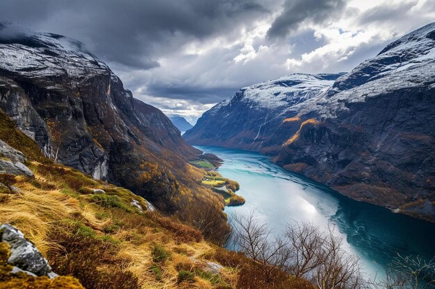 Lengua de troll sobre el fiordo en el desfiladero de Noruega con cielos nublados y cumbres nevadas