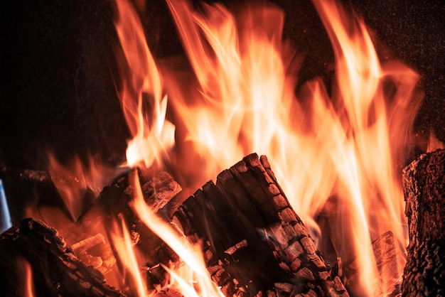 Lenguas de fuego naranja sobre fondo negro en una chimenea de ladrillo