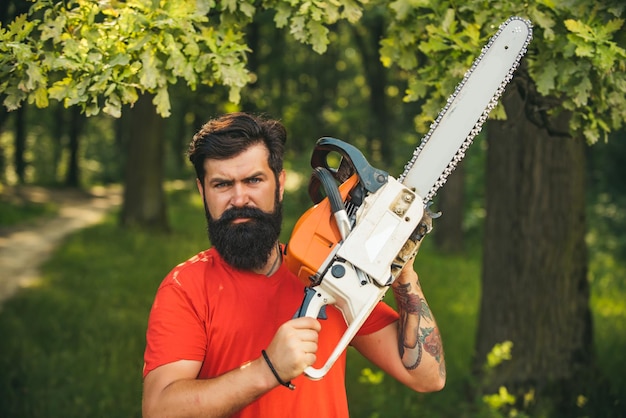 Lenhador em cara séria carrega motosserra O desmatamento é uma das principais causas da degradação da terra e desestabilização dos ecossistemas naturais Homem fazendo o trabalho do homem